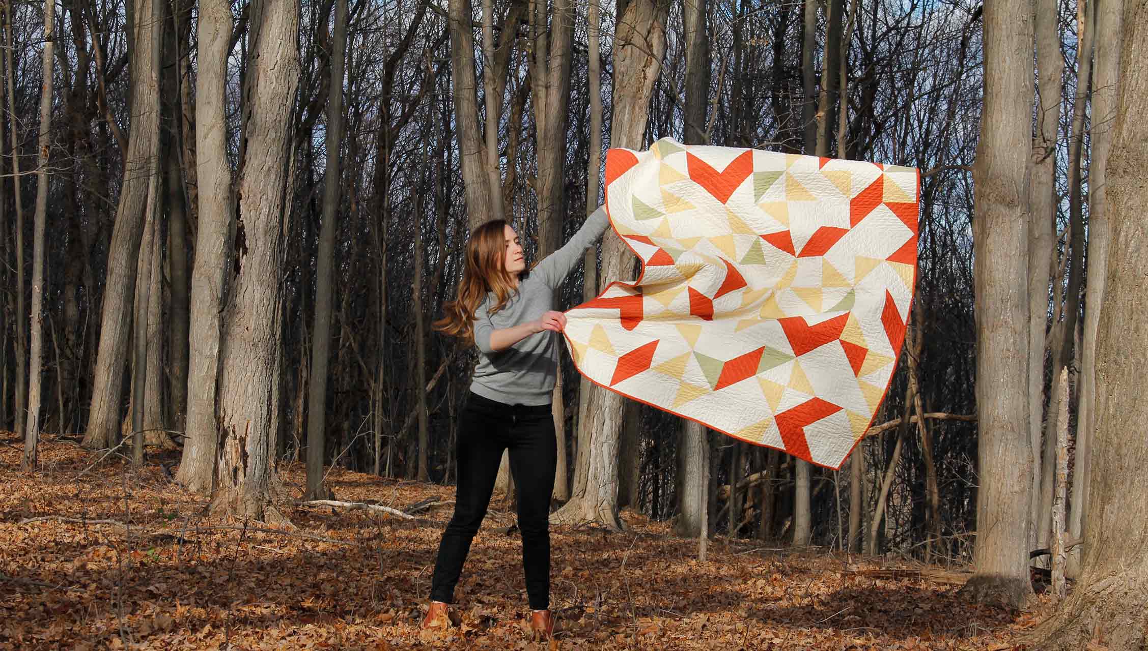 Person shaking quilt in a forest